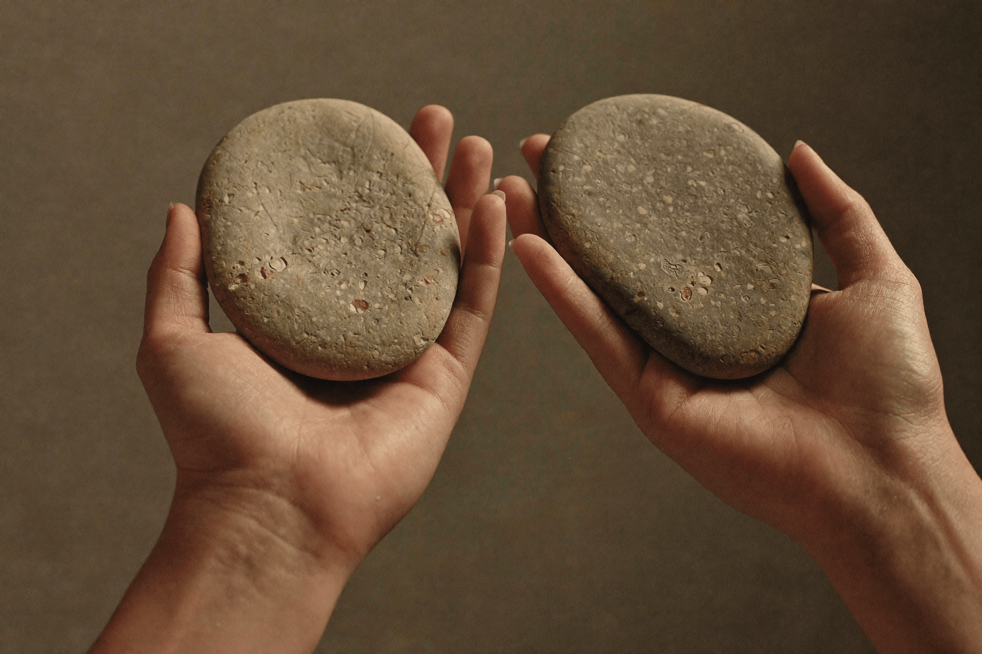 Due mani confrontano due pietre identiche, simbolo della percezione di valore